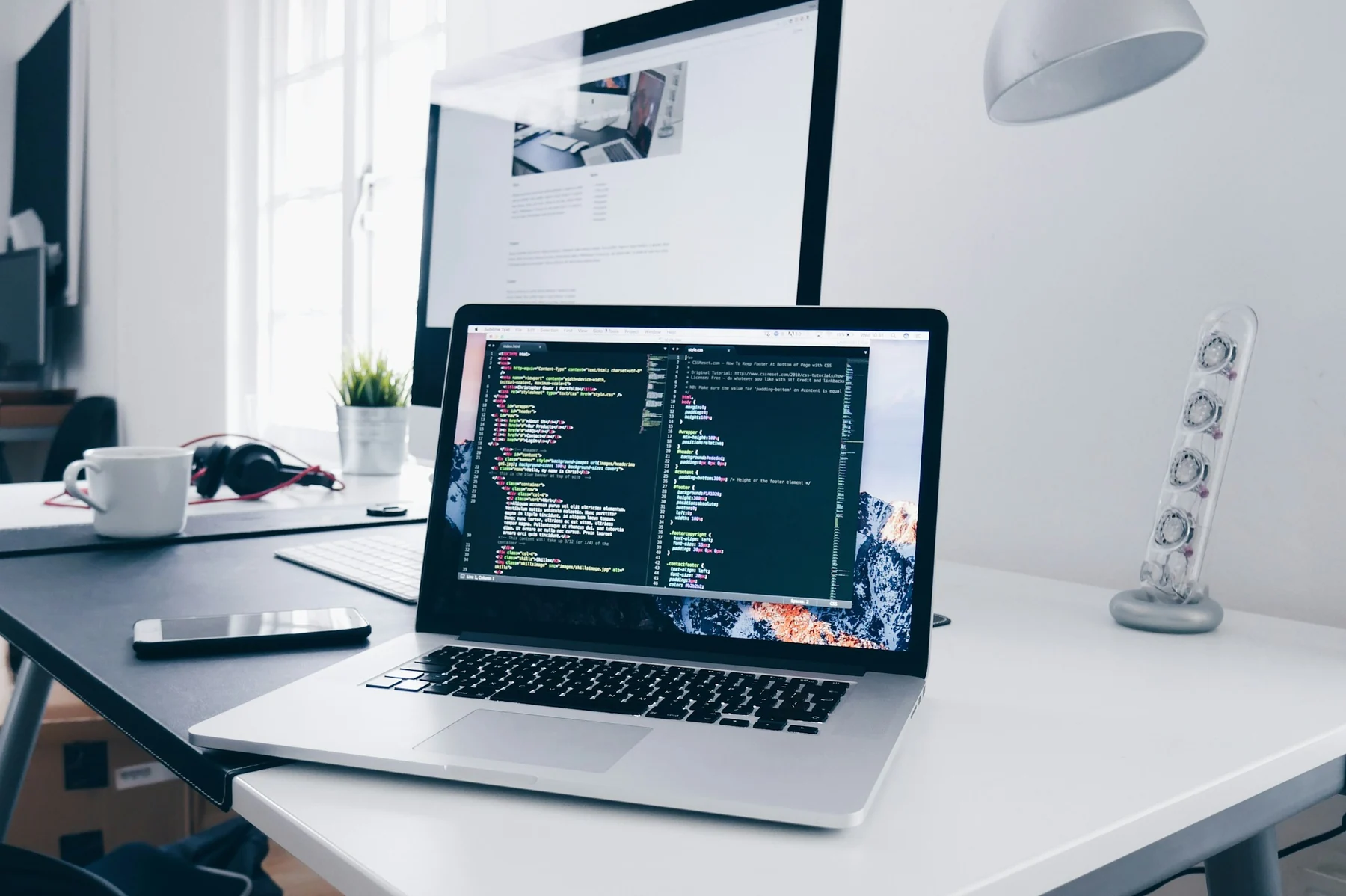 Laptop showing code in a bright desktop workspace