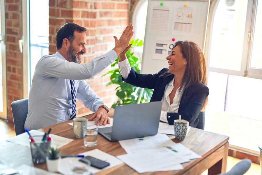 Two business professionals celebrating across a meeting table